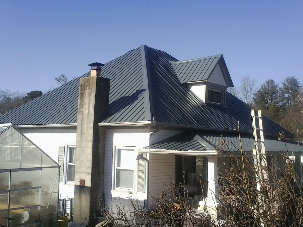 Dark blue standing seam metal roof on a white farmhouse with dormer — Slate & Tile Roof Repair by Roofing Brothers in West Park