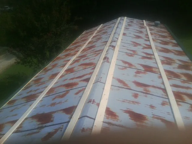 Rusted metal roof panels with new wood purlins before replacement — Storm Damage Roof Repair in West Park by Roofing Brothers
