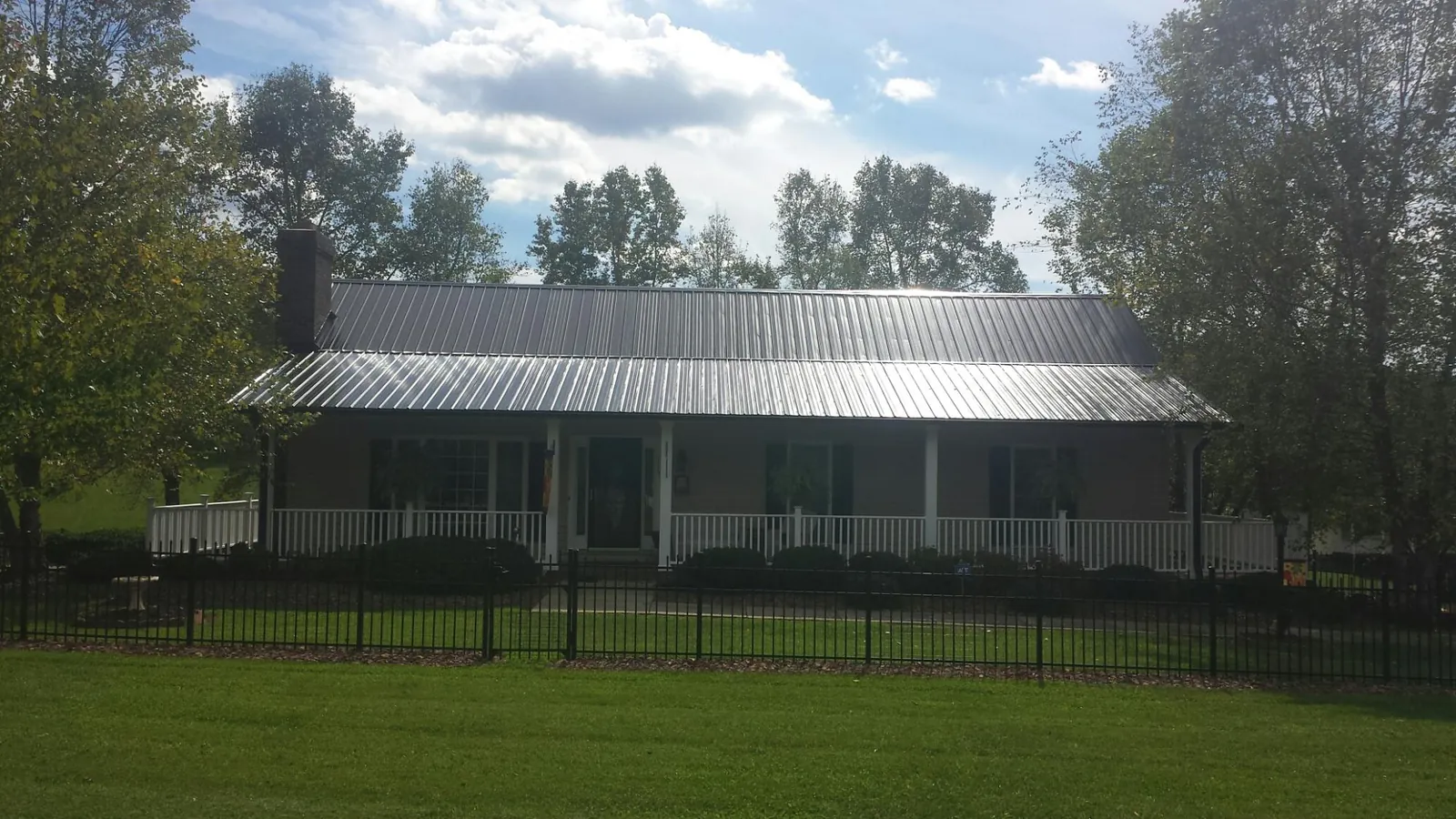 Gray metal roof on a brick ranch with a full width front porch — Gutter Guard Installation work by our crew in West Park