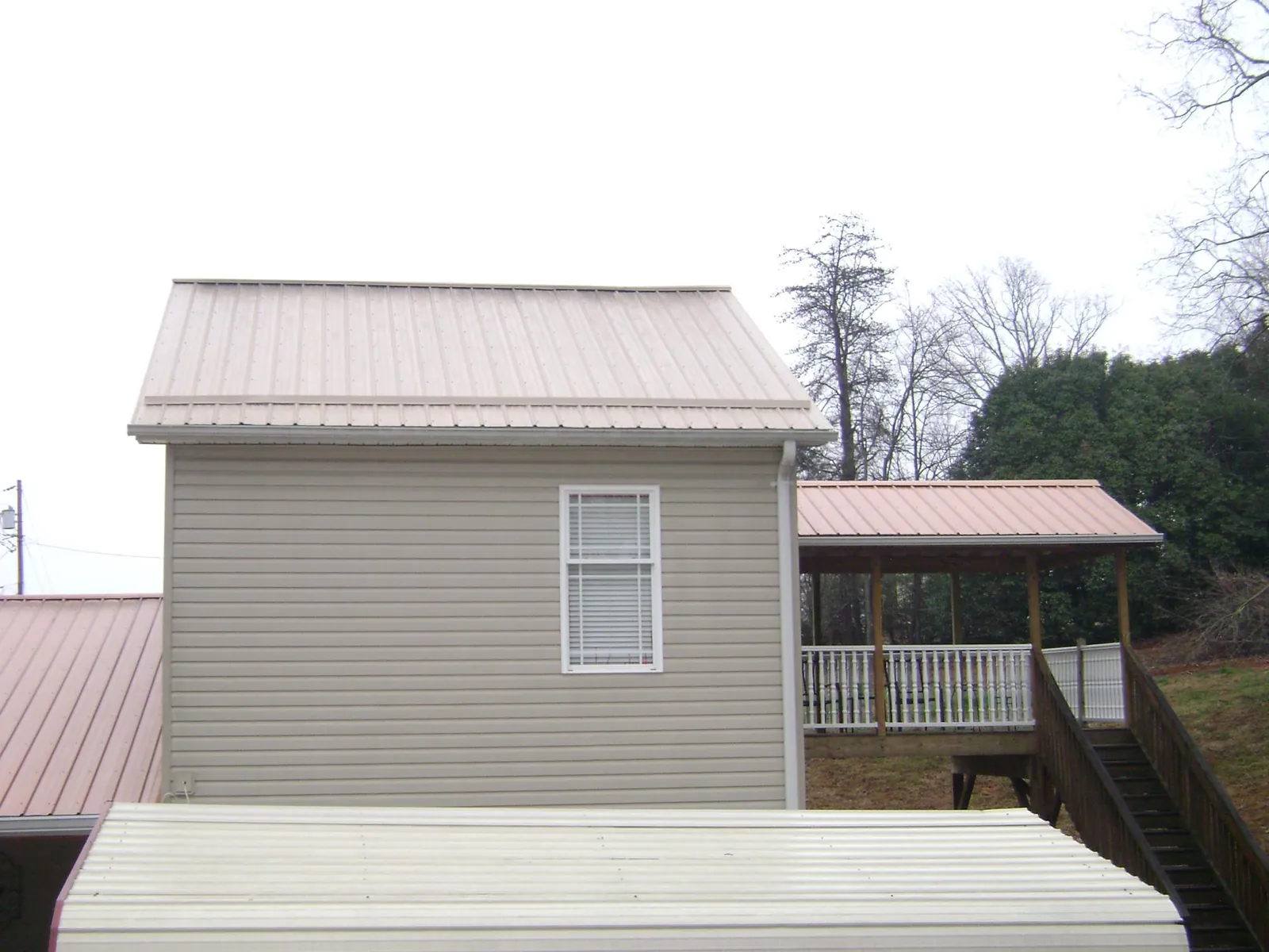 Tan metal roofs on a two story addition and attached porch, from a Roof Replacement job in West Park