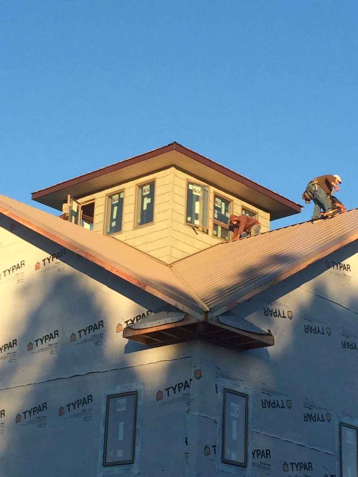 Roofers working around a rooftop cupola on a new metal roof at sunset — Roof Waterproofing in West Park by Roofing Brothers
